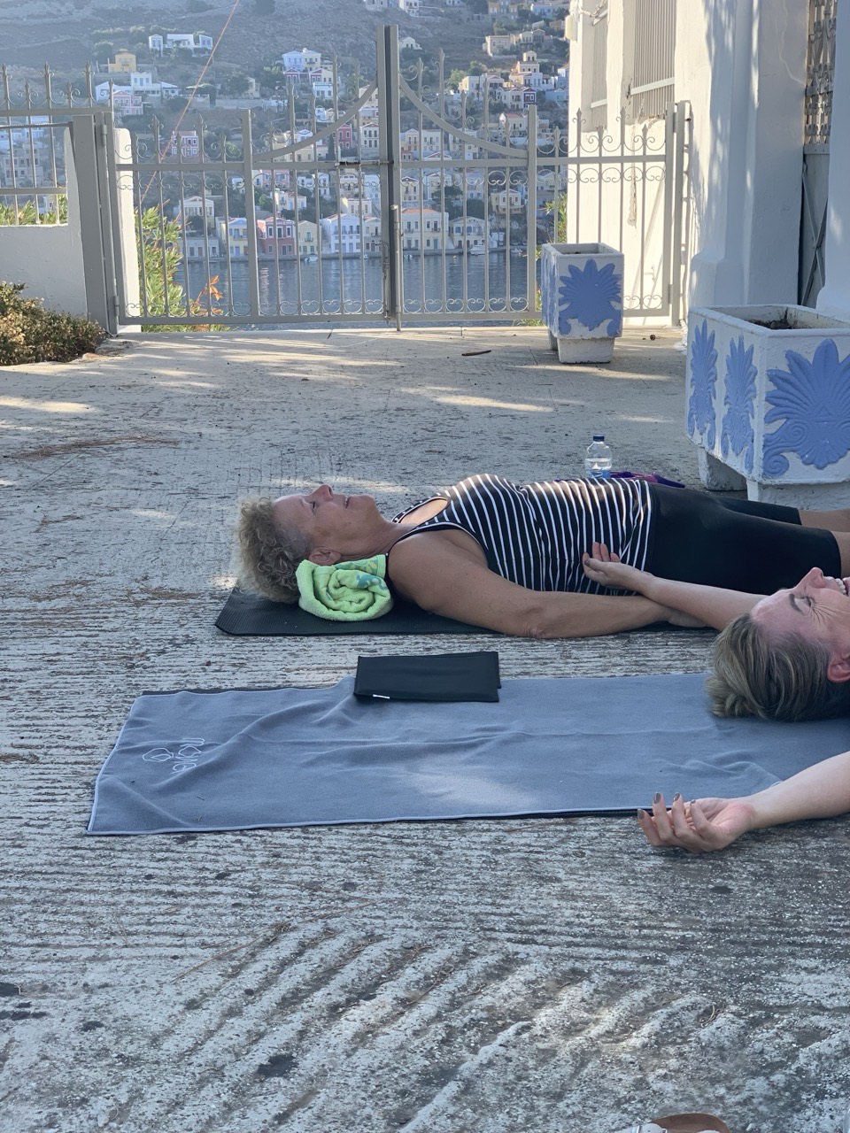 Deltagere i afspænding på yogamåtter med udsigt over Symi havn
